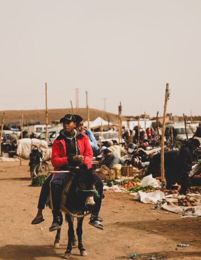 Geführte Wohnmobilreise durch Marokko | Kinder reiten auf einem Esel über den Souk in Zagora